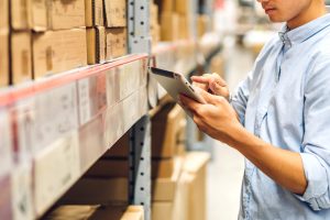 Portrait of smiling asian engineer man order details checking goods and supplies on shelves with goods background in warehouse.logistic and business export